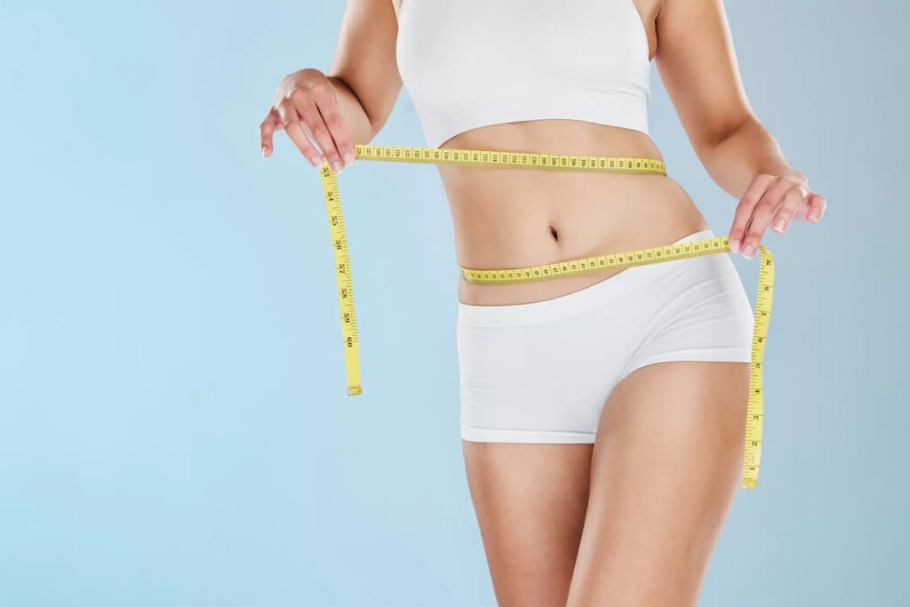 a woman measuring her waist after medical weight loss